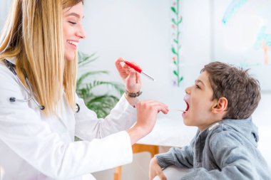 Çocuk doktoru çocuklar boğaz kalem meşale ve dil depressor ile incelenmesi 