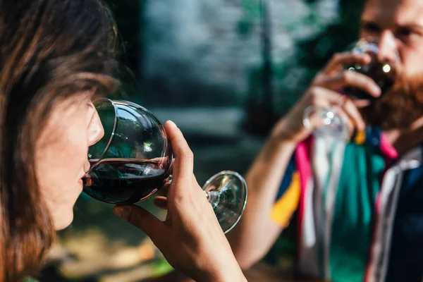 若いカップルのロマンチックなワインの日に試飲を楽しんでします カップル着てカラフルな衣装 バック グラウンドでの屋外レストラン — ストック写真