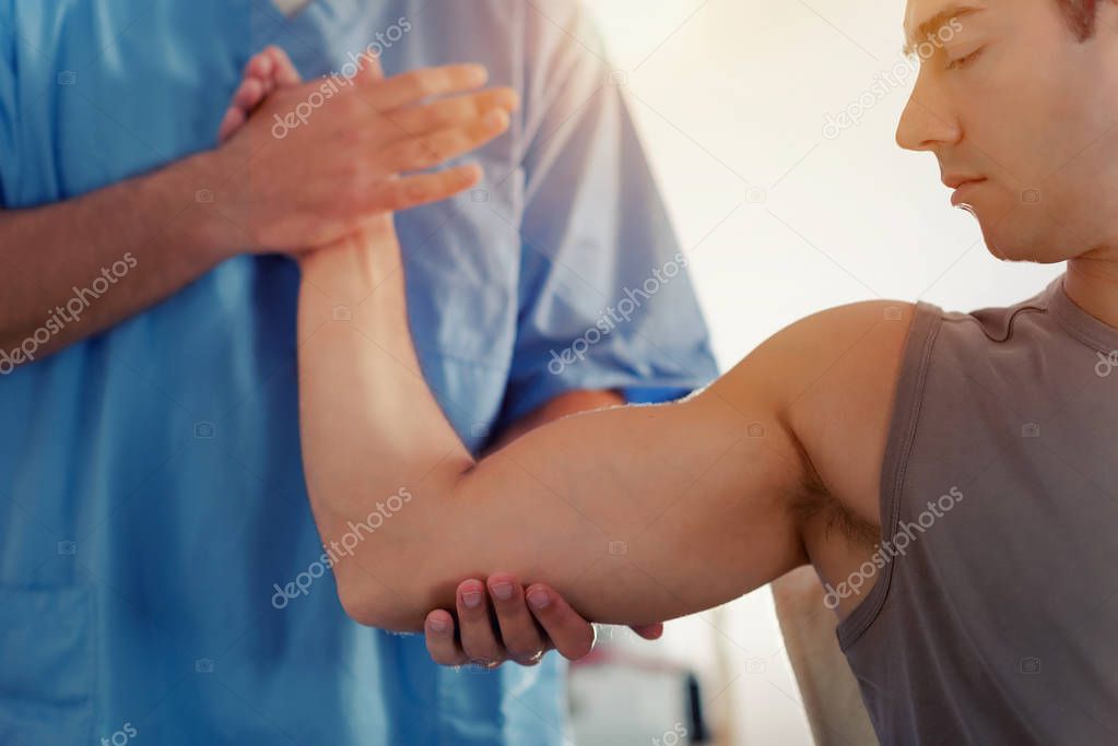 Physiotherapist doing healing treatment on man's arm, Therapist wearing blue uniform, Osteopath,  Chiropractic adjustment, 