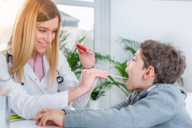 Çocuk doktoru çocuklar boğaz kalem meşale ve dil depressor ile incelenmesi 
