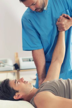 Adamın kolu, iyileştirici tedavi yaparken mavi üniforma giyen terapist, kırıkçı, Chiropractic ayarlama, Masaj masanın üzerinde yatan hasta fizyoterapist
