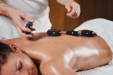 Güzel ve genç birbayan Başlarken sıcak taş spa salonunda masaj