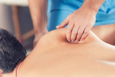 Fizyoterapist adamın sırtına iyileştirici tedavi yapıyor. Terapist mavi üniforma giydiği bildirildi. Osteopati. Chiropractic ayarlama