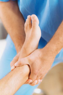 Fizyoterapist iyileştirici tedavi hasta ayak yapıyor. Terapist mavi üniforma giydiği bildirildi. Osteopati, Chiropractic ayak ayarlama