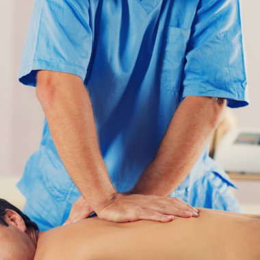 Fizyoterapist adamın sırtına iyileştirici tedavi yapıyor. Terapist mavi üniforma giydiği bildirildi. Osteopati. Chiropractic ayarlama, Masaj masanın üzerinde yatan hasta