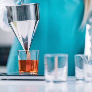 Dökme turuncu balmumu ile yapıştırılmış ahşap fitil cam içine erimiş ve üzerinde dijital ölçek ölçmek. Koruyucu iş giysisi giymiş. Mum yapma süreç