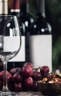 Boş şarap cam, farklı şişe kırmızı şarap, ahşap kase ve taze üzüm fındık ile kompozisyon. Yakın çekim.