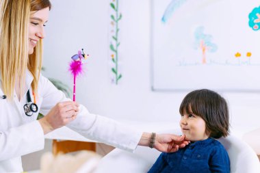 Pediatrician examining little boys eyesight  clipart