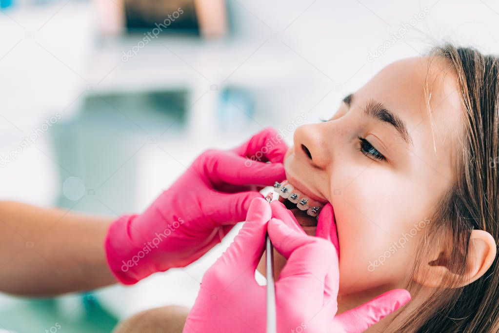 Orthodontist fixing girls dental braces 