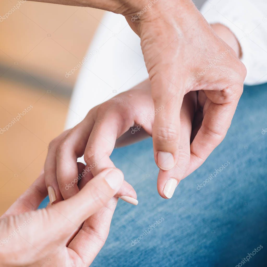 Close up square image of female hands performing muscle testing at Theta healing session. Therapist and patient sitting and wearing white clothes. Energy healing concept