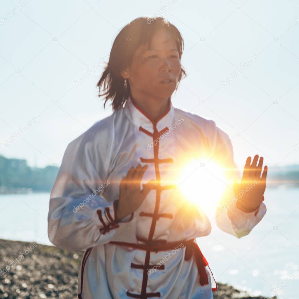 woman performing Tai Chi by the lake