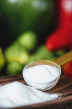 Kollajen protein masada plastik kaşık ve taze renkli sebzeler ile konteyner toz takviyeleri. Sağlık ve güzellik takviyesi kavramı