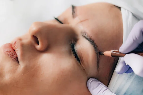 Beautician Addressing the Shape of the Brows Before Microblading.  Semi-Permanent Makeup