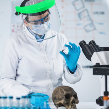 Antik DNA analizi. Antik DNA laboratuvarında örnek li mikro tüp tutan kadın bilim adamı.