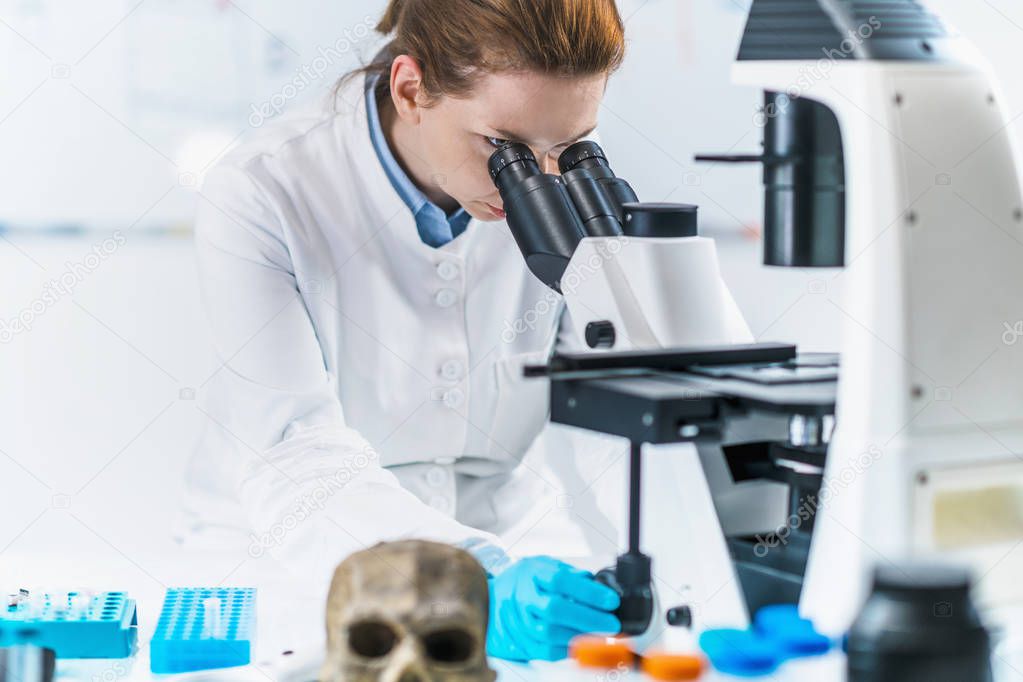 Portrait of young female bioarchaeologist with microscope in a lab