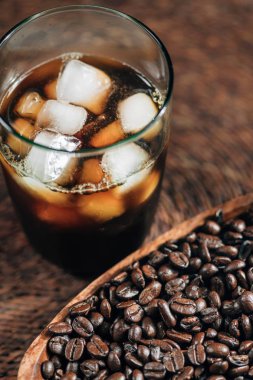 Buz küpleri ve ahşap kase kavrulmuş kahve çekirdekleri ile cam fincan soğuk demlemek buzlu kahve. Kahve konsepti yapma