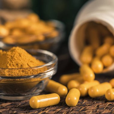 Curcumin bitkisel ek kapsül ve cam kase zerdeçal tozu. Anti-inflamatuar bitkisel ilaç (Curcuma) 