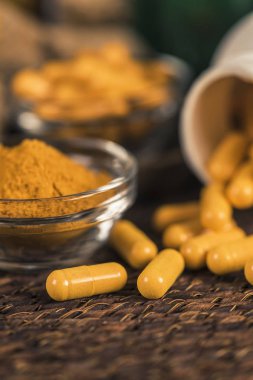 Curcumin bitkisel ek kapsül ve cam kase zerdeçal tozu. Anti-inflamatuar bitkisel ilaç (Curcuma) 