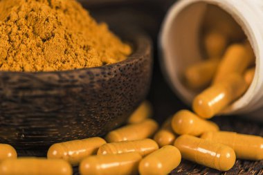 Curcumin bitkisel ek kapsül ve cam kase zerdeçal tozu. Anti-inflamatuar bitkisel ilaç (Curcuma) 