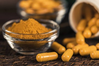 Curcumin bitkisel ek kapsül ve cam kase zerdeçal tozu. Anti-inflamatuar bitkisel ilaç (Curcuma) 