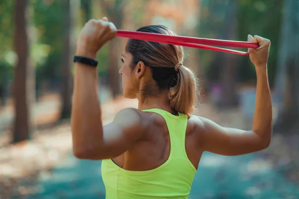Woman Exercising with Elastic Resistance Band in the Park