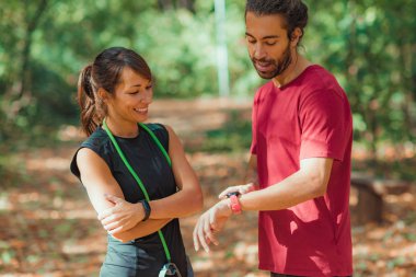 Genç çift, açık hava eğitiminden sonra akıllı saatlerini kontrol ediyor.