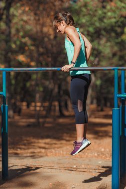 Parktaki paralel barda antrenörle egzersiz yapan bir kadın.