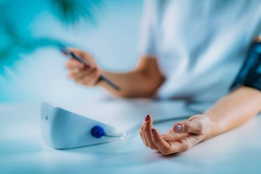 Mobil sağlık - Kan Basıncını Ölçen ve Akıllı Telefondan Veri Giren Kadın