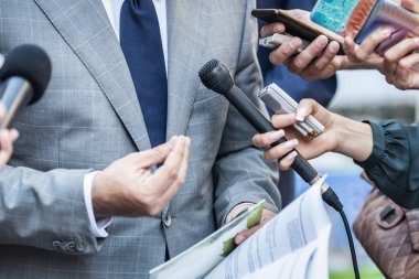 Medya Röportajı - mikrofonlu gazeteciler resmi giyinmiş politikacı veya işadamıyla röportaj yapıyorlar.