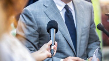 Medya Röportajı - mikrofonlu gazeteciler resmi giyinmiş politikacı veya işadamıyla röportaj yapıyorlar.