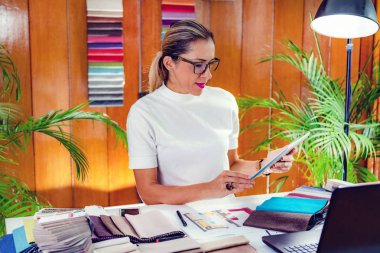 Kadın dekoratör ofisindeki dijital tablette kat planına bakıyor.