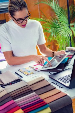 Kadın dekoratör ofisindeki dijital tablette kat planına bakıyor.