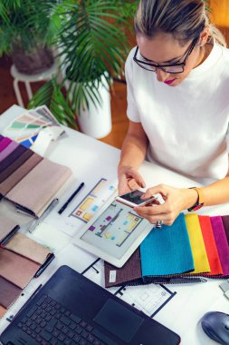 Ofiste akıllı telefon kullanan bir bayan dekoratör.