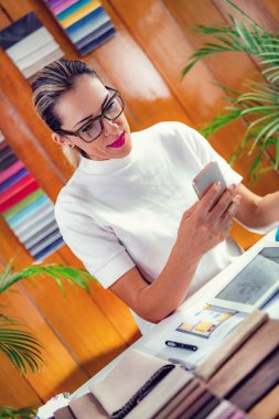 Ofiste akıllı telefon kullanan bir bayan dekoratör.