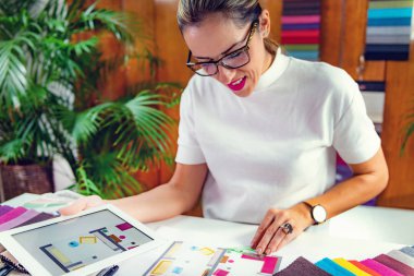 Kadın dekoratör ofisindeki dijital tablette kat planına bakıyor.