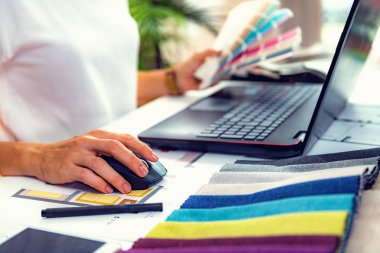 Mimar, iç mimar, malzeme örnekleri ve ofiste dizüstü bilgisayar üzerinde çalışıyor.