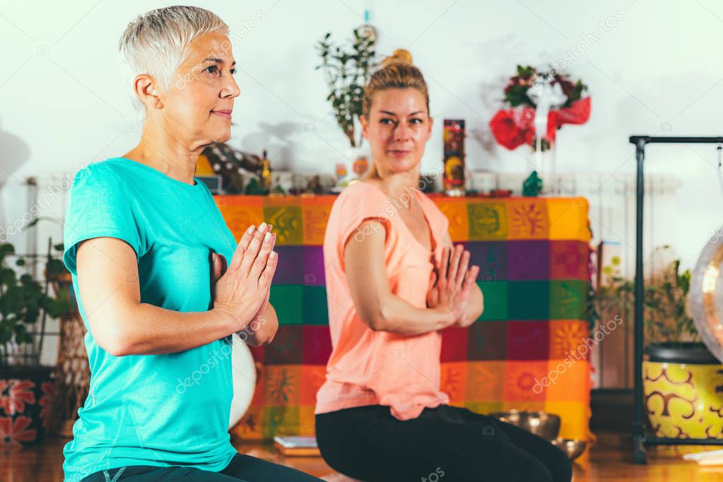 Yoga guru with senior woman, doing yoga