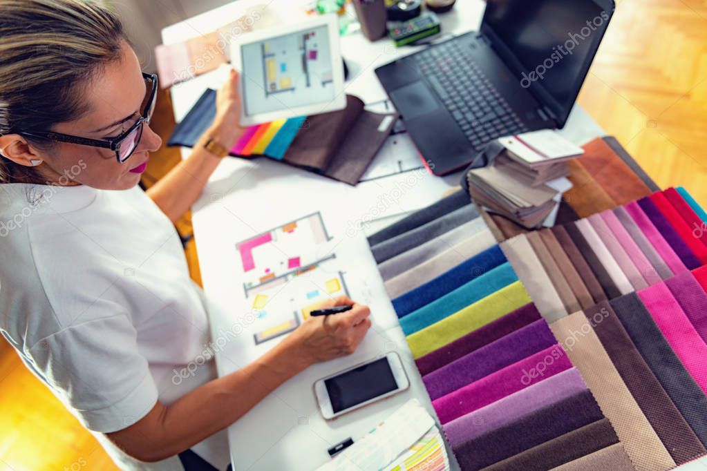 Female architect, decorator, drawing floor plan in her office