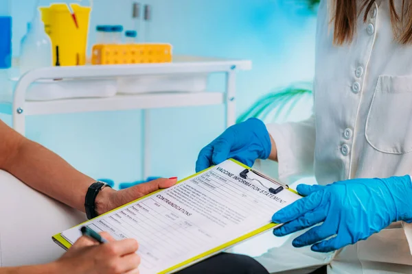 Female Patient Filling in Vaccine Information Statement. Corona Virus Vaccination.