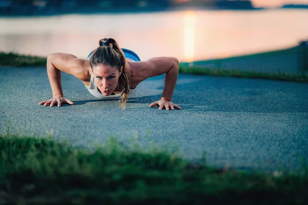 Push-Ups. Woman Exercising Outdoors by The Lake