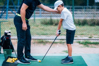 Golf dersleri. Golf hocası genç bir çocuğa oyun dersi veriyor..