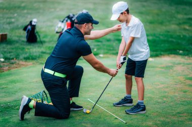 Golf dersleri. Golf hocası genç bir çocuğa oyun dersi veriyor..