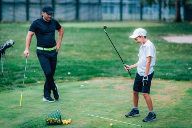 Golf Dersi. Golf Eğitmeni Genç Çocuğa Nasıl Sallanacağını Öğretiyor 