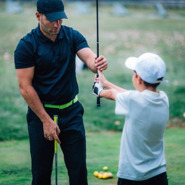 Golf eğitmeni, genç oğlanların elini tutuyor.  