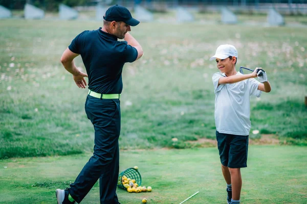 高尔夫课 一名高尔夫教练和一名在高尔夫练习场练习的男孩 — 图库照片