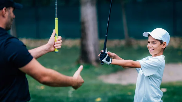 高尔夫教练调整小男孩的握力 — 图库照片