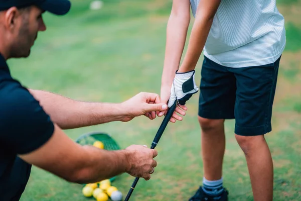 高尔夫教练调整小男孩的握力 — 图库照片