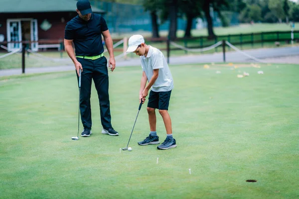 学习高尔夫 男孩和教练一起练习放水 — 图库照片
