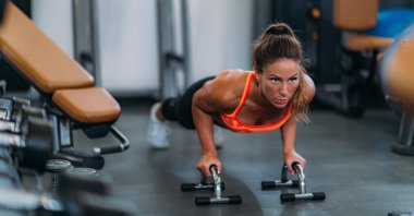 Spor salonunda şınav çeken bayan sporcu.