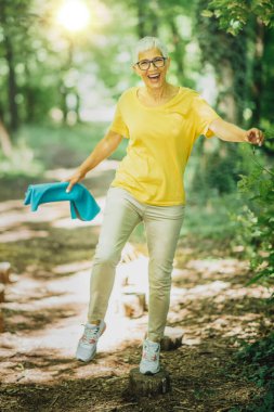 Açık havada denge egzersizi. Olgun bir kadın tek ayak üzerinde duruyor, denge kuruyor. 